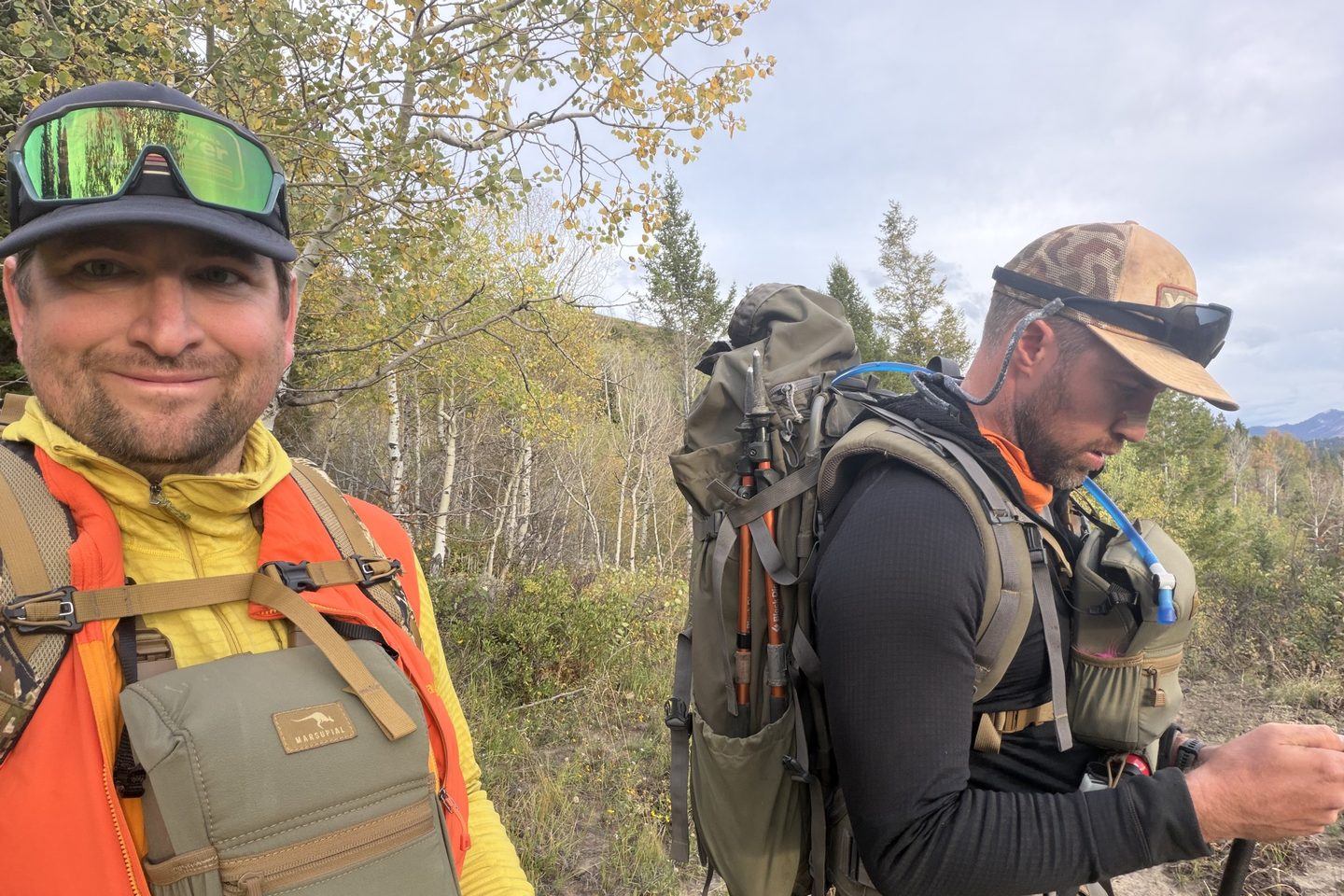 Wim Roach and Brian Lorenz on the trail during an Idaho moose hunt, with packs on and aspens turning yellow behind them